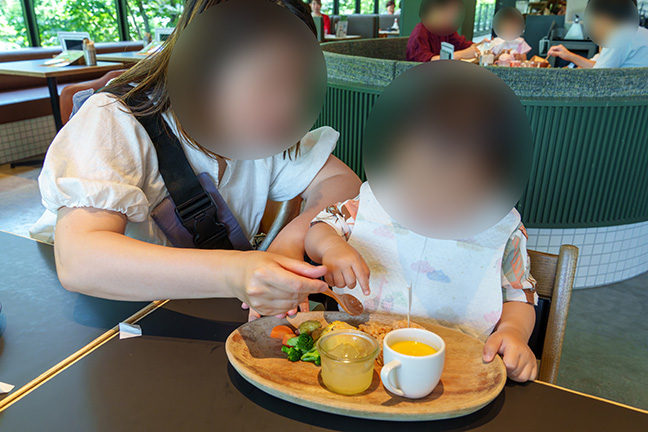 100本のスプーンのキッズプレートを食べる1歳児