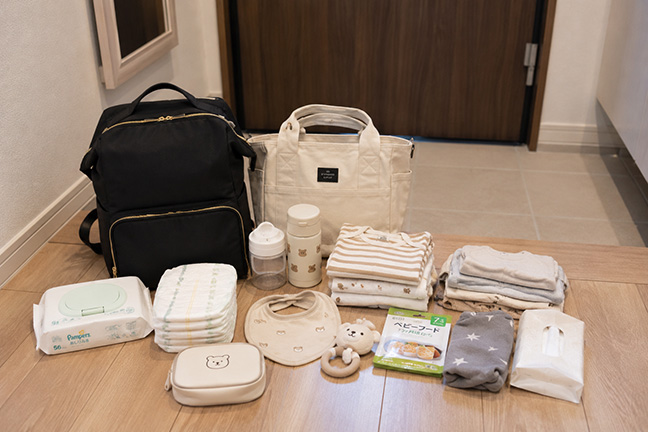 子どもとのお出かけで必要な荷物を玄関に並べた様子（イメージ）