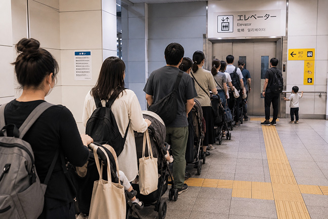 ベビーカーで駅のエレベーターを待つ人たちのイメージ